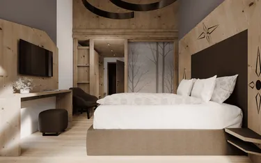 Camera da letto con pareti di legno, grande letto con coperte bianche, decorazioni a tema montagna sui muri, e un'area con televisore e sedie.