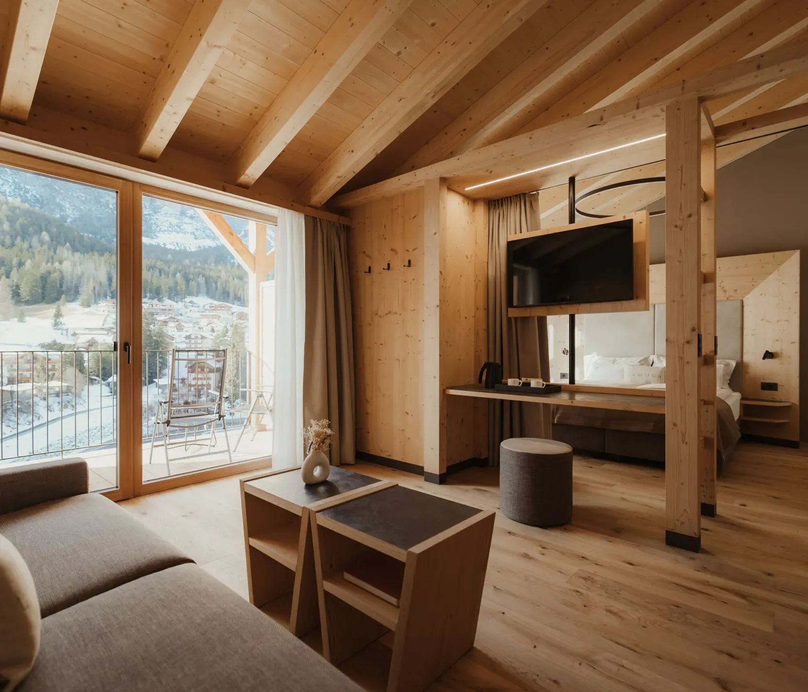 Warm, cozy room with wooden interior, large windows revealing a snowy mountain view. Soft lighting, modern furniture, and tranquil ambiance.